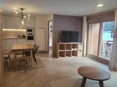 a kitchen and living room with a table and a television at Le Hameau des Glaciers - Ski & Vue Incroyable in Les Houches