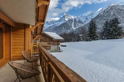 a balcony with two chairs and snow covered mountains at Le Hameau des Glaciers - Ski & Vue Incroyable in Les Houches