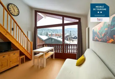 a bedroom with a balcony with a clock and a table at Les Eterlous N44 2P6 in Morillon
