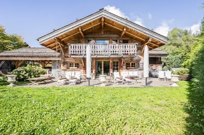 a large log house with a deck and patio at Luxury Stay Comfortable Chalet with Jacuzzi in Megève