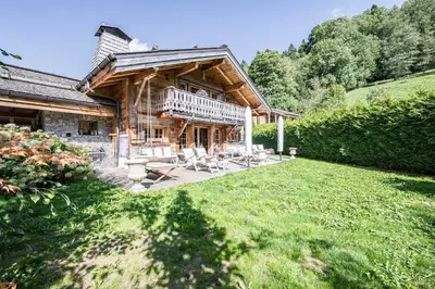a large log house with a lawn in front of it at Luxury Stay Comfortable Chalet with Jacuzzi in Megève
