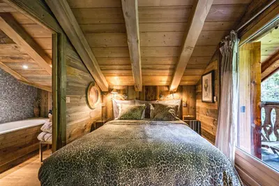 a bedroom with a bed in a room with wooden walls at Luxury Stay Comfortable Chalet with Jacuzzi in Megève
