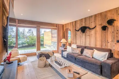 a living room with a brown couch and wooden walls at Appartement Reflet des Cimes - Welkeys in Megève