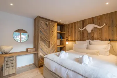 a bedroom with a large bed and a wooden wall at Appartement Reflet des Cimes - Welkeys in Megève