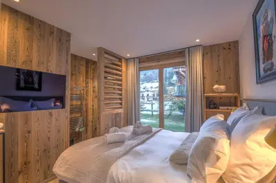a bedroom with a large white bed with a window at Appartement Reflet des Cimes - Welkeys in Megève
