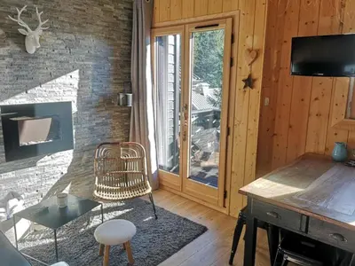 a living room with a fireplace and a table and chair at Studio mezzanine à 300m des pistes, balcon sud, jusqu'à 4 personnes - FR-1-572-342 in Arâches-la-Frasse