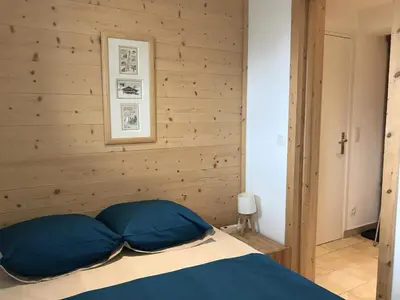 a bedroom with wooden walls and a bed with blue pillows at Appartement rénové 1 chambre avec balcon, parking et wifi centre station - FR-1-836-62 in Arâches-la-Frasse