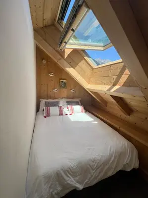 a bed in a small room with a window at Chamonix Trailside Town Apartments in Chamonix-Mont-Blanc