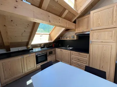 a kitchen with wooden cabinets and a white table at Chamonix Trailside Town Apartments in Chamonix-Mont-Blanc