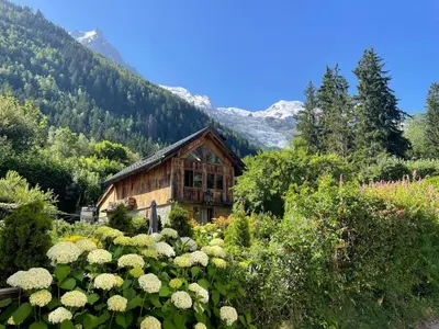 a house in the middle of a garden with flowers at Chamonix Trailside Town Apartments in Chamonix-Mont-Blanc