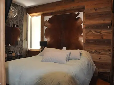 a bedroom with a large bed with a wooden wall at Appartement rénové 2 chambres, centre station, 300m des pistes, 6 pers, WiFi - FR-1-836-63 in Arâches-la-Frasse