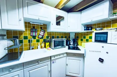 a kitchen with white cabinets and yellow tiles on the wall at Bright studio with a view of Mont Blanc in Chamonix-Mont-Blanc
