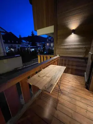a wooden bench sitting on a wooden deck at night at Charmant appartement en plein centre in Megève