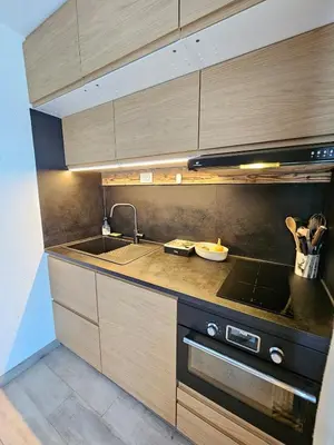 a kitchen with wooden cabinets and a sink at appartement proche ski et randonnées, vue montagne in Saint-Gervais-les-Bains