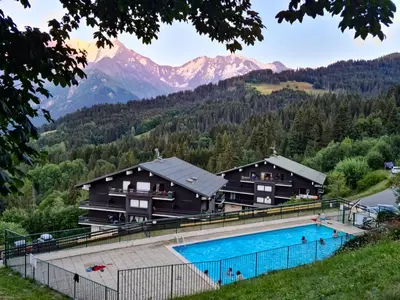 a resort with a swimming pool and mountains in the background at appartement proche ski et randonnées, vue montagne in Saint-Gervais-les-Bains