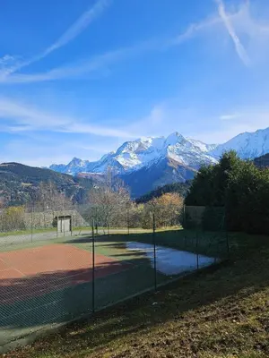 a tennis court with snow capped mountains in the background at appartement proche ski et randonnées, vue montagne in Saint-Gervais-les-Bains