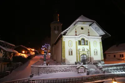 a large white building with a clock tower at night at Les Dômes - Appartement centre village et superbe vue montagne in Les Contamines-Montjoie