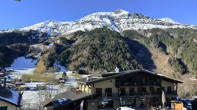 a balcony with a view of a building with a snow covered mountain at Les Dômes - Appartement centre village et superbe vue montagne in Les Contamines-Montjoie