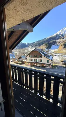 a building with a tower with a clock on it at Les Dômes - Appartement centre village et superbe vue montagne in Les Contamines-Montjoie