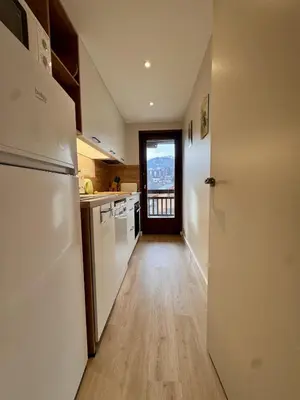 a kitchen with white appliances and a hallway with a door at Le Saphir Montagne & Ski in Saint-Gervais-les-Bains