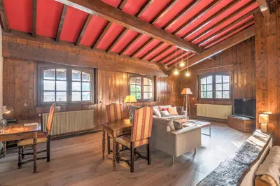 a living room with wooden walls and red beams at Demi-chalet Le pré du loup - Welkeys in Megève