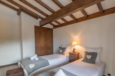 two twin beds in a room with wooden ceilings at Demi-chalet Le pré du loup - Welkeys in Megève