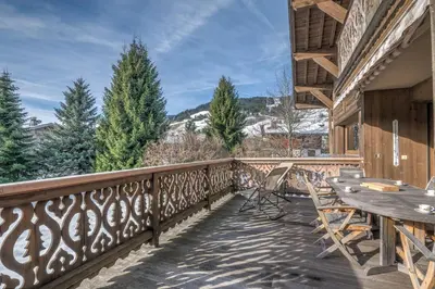 a wooden balcony with a table and chairs on it at Demi-chalet Le pré du loup - Welkeys in Megève