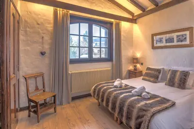 a bedroom with a bed and a window and a chair at Demi-chalet Le pré du loup - Welkeys in Megève