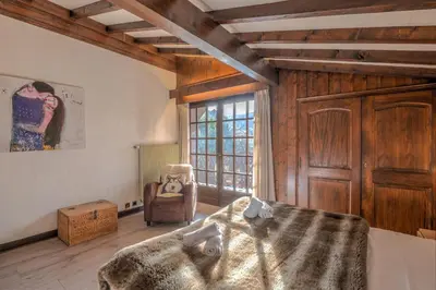 a bedroom with a bed and a chair and a window at Demi-chalet Le pré du loup - Welkeys in Megève