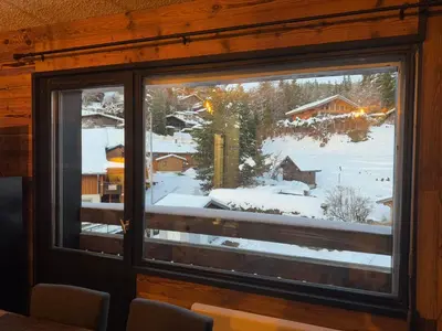 a window in a cabin with a view of a snow covered yard at Studio COCOONING LE CARIBOU in Les Carroz d'Araches