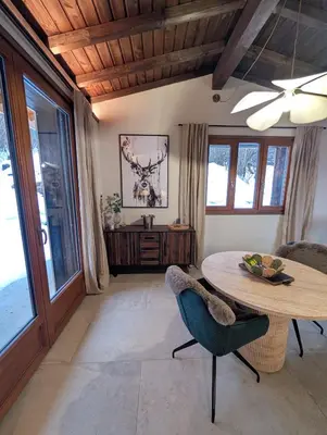 a living room with a table and chairs and windows at Stunning New Apartment in Chamonix with Mont Blanc Views in Chamonix-Mont-Blanc