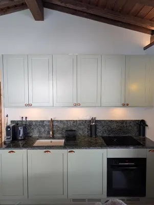 a kitchen with white cabinets and a sink at Stunning New Apartment in Chamonix with Mont Blanc Views in Chamonix-Mont-Blanc