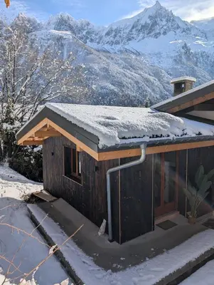 a house covered in snow with mountains in the background at Stunning New Apartment in Chamonix with Mont Blanc Views in Chamonix-Mont-Blanc