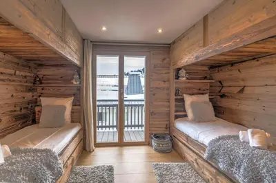 two beds in a room with wooden walls at Appartement Thoret - 3 étoiles - Welkeys in Megève