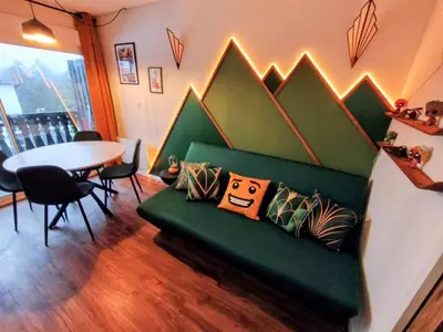 a living room with a green couch and a table at Gamebox in Carroz in Les Carroz d'Araches