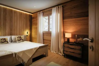 a bedroom with wooden walls and a bed with a window at Chalet Alpage du Bettex - OVO Network in Mémontel