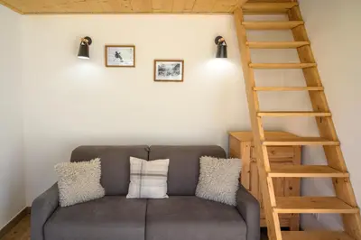 a living room with a gray couch and a wooden ladder at Le Saint Gervolain in Saint-Gervais-les-Bains