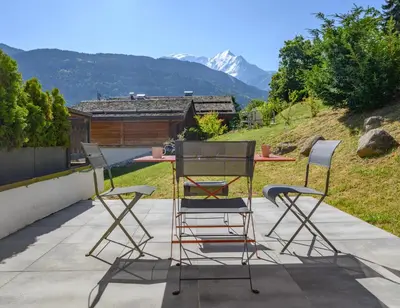 a table and chairs on a patio with a mountain at Le Saint Gervolain in Saint-Gervais-les-Bains