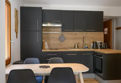 a kitchen with a table with chairs and a refrigerator at Le Saint Gervolain in Saint-Gervais-les-Bains