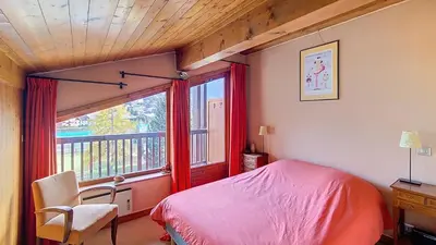 a bedroom with a bed and a window and a chair at 1 Sporting Acacia 2 - JAILLET - in Megève