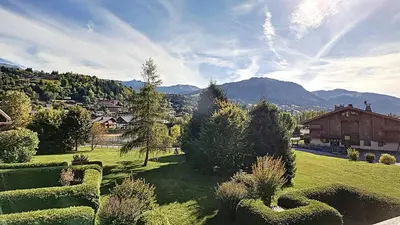 a view of a green yard with mountains in the background at 1 Sporting Acacia 2 - JAILLET - in Megève