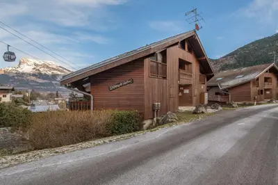 a building on the side of a road with a mountain at Appartement Le Nid des Sommets - Welkeys in Saint-Gervais-les-Bains