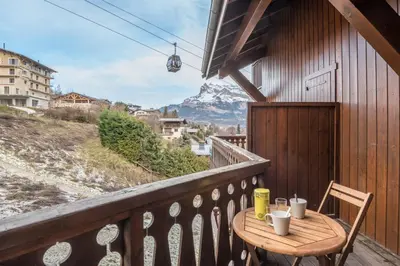 a table on a balcony with a view of a mountain at Appartement Le Nid des Sommets - Welkeys in Saint-Gervais-les-Bains