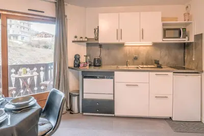 a kitchen with white cabinets and a large window at Appartement Le Nid des Sommets - Welkeys in Saint-Gervais-les-Bains