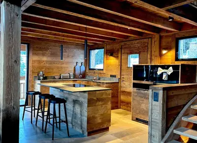 a kitchen with wooden walls and a island with bar stools at Chalet de l'Emey - 12 pers in Mémontel