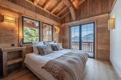 a bed in a room with wooden walls and windows at Chalet de l'Emey - 12 pers in Mémontel