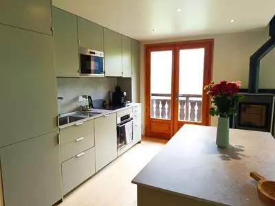 a kitchen with white cabinets and a vase of flowers at Le Cairn in Saint-Gervais-les-Bains