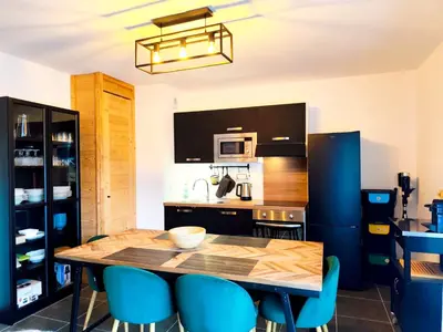 a kitchen with a wooden table and blue chairs at L'Alpin C in Le Fayet