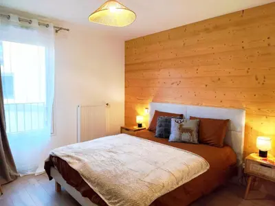 a bedroom with a large bed with a wooden wall at L'Alpin C in Le Fayet
