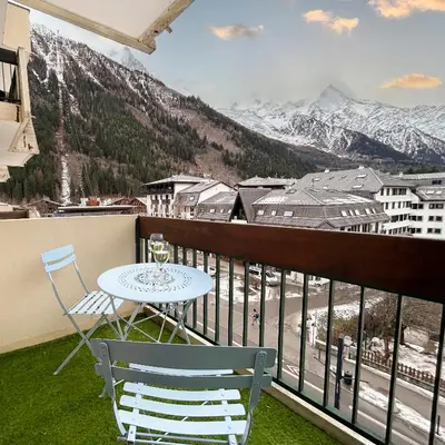 a balcony with a table and chairs and mountains at Appart Hyper Centre Chamonix balcon parking privé in Chamonix-Mont-Blanc